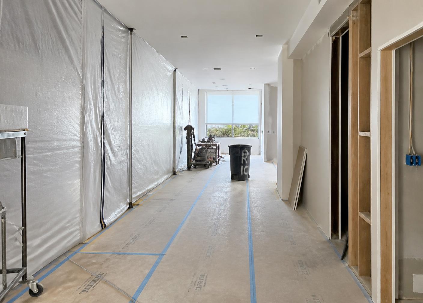Interior reconstruction site with protected floors, containment barriers and exposed wall framing during building repairs